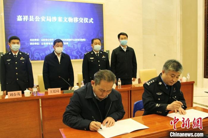 山東博物館館長(zhǎng)鄭同修和嘉祥縣人民政府副縣長(zhǎng)、公安局局長(zhǎng)趙健簽署移交協(xié)議。　趙曉 攝