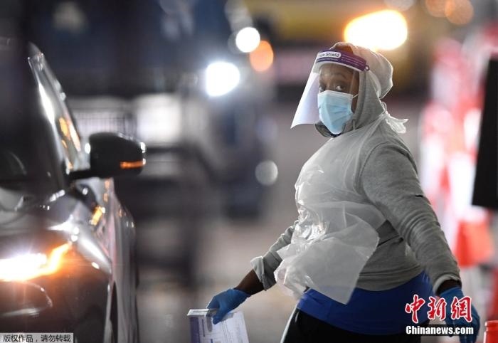 當(dāng)?shù)貢r(shí)間12月18日，英國(guó)政府公布的數(shù)據(jù)顯示，當(dāng)天英國(guó)新增奧密克戎毒株感染病例10059例。鑒于奧密克戎毒株感染病例激增，住院人數(shù)不斷上升，倫敦市長(zhǎng)宣布倫敦進(jìn)入“重大事故”狀態(tài)。圖為倫敦的一個(gè)免下車(chē)檢測(cè)中心，一名醫(yī)務(wù)工作者正準(zhǔn)備對(duì)司機(jī)進(jìn)行核酸檢測(cè)。