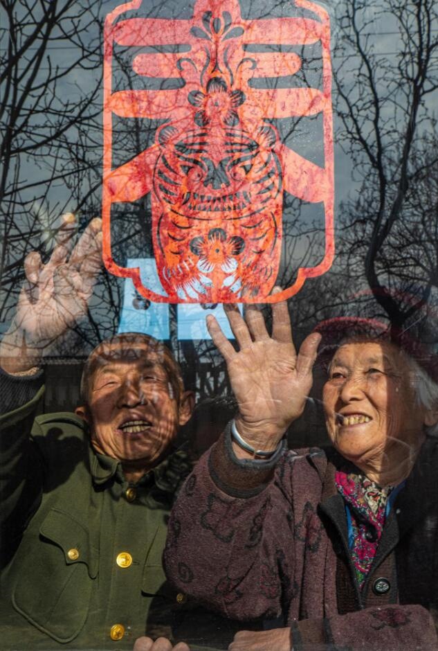 臘月里，霍州市師莊鄉(xiāng)馮南垣村村民師榮光(左)在災(zāi)后重建的新家里貼窗花。(霍州市委宣傳部供圖)