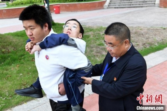 朱金祥背著鐘華強去教室上課的路上，也經(jīng)常碰到值班的校領(lǐng)導(dǎo)和老師前來搭把手。 卓忠偉 攝