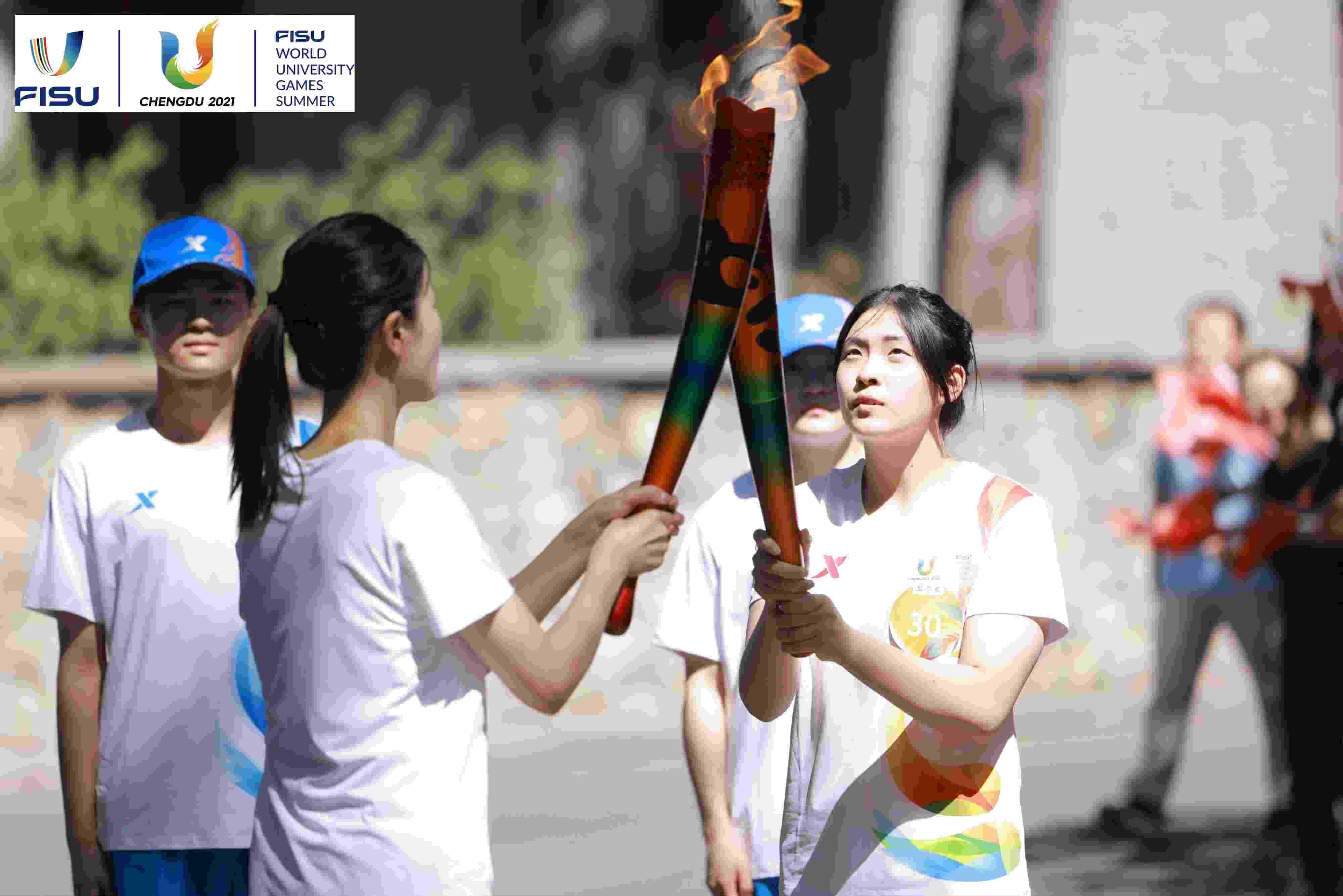 兩名大運(yùn)會(huì)火炬手進(jìn)行火炬?zhèn)鬟f。 圖片來(lái)源：成都大運(yùn)會(huì)執(zhí)委會(huì)供圖