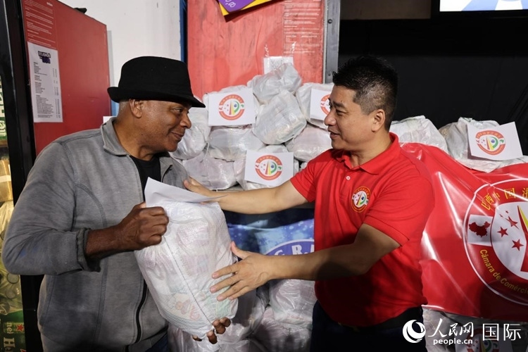 巴西中國(guó)浙江商會(huì)會(huì)長(zhǎng)鄭俠茂向社區(qū)居民轉(zhuǎn)交捐贈(zèng)物資。人民網(wǎng)記者 時(shí)元皓攝