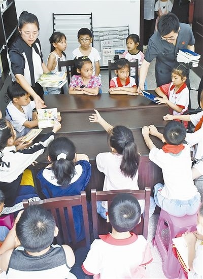  圖④：法院干警為留守兒童發(fā)放暑假讀物。