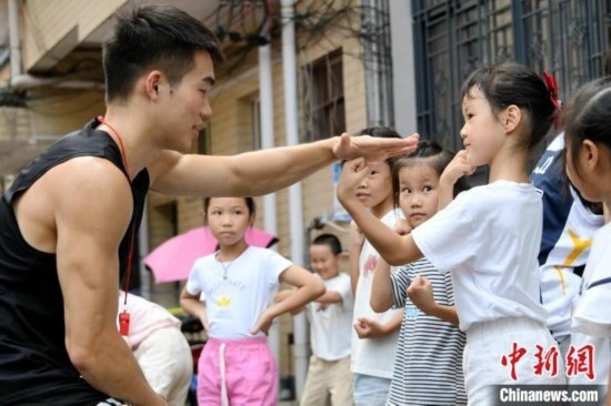 圖為大學(xué)生志愿者在組織孩子們參加體育健身活動。廖光福 攝