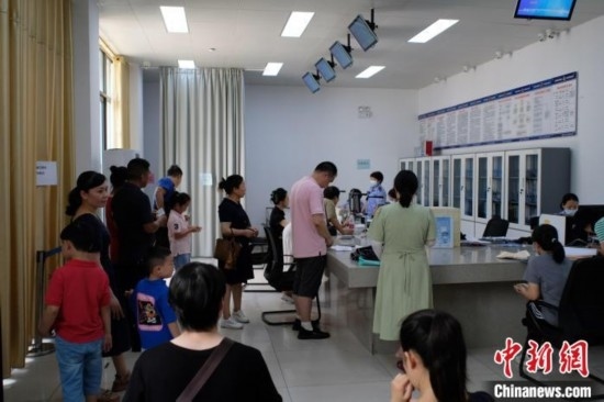 圖為在戶籍辦證廳內(nèi)排隊(duì)等待的家長和孩子。劉俊聰 攝