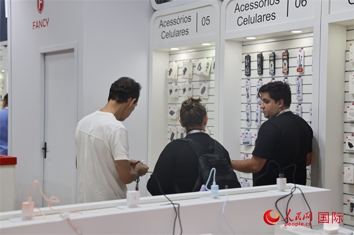 幾名參觀者在一個展臺前了解手機配件。（人民網(wǎng)記者 時元皓攝）