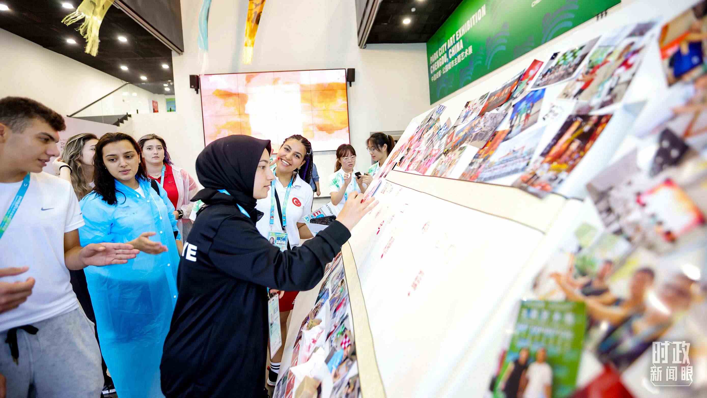 各國(guó)青年運(yùn)動(dòng)員正在參觀成都大運(yùn)村內(nèi)的“雪山下的公園城市，煙火里的幸福成都”主題藝術(shù)展。（總臺(tái)央視記者魏幫軍拍攝）