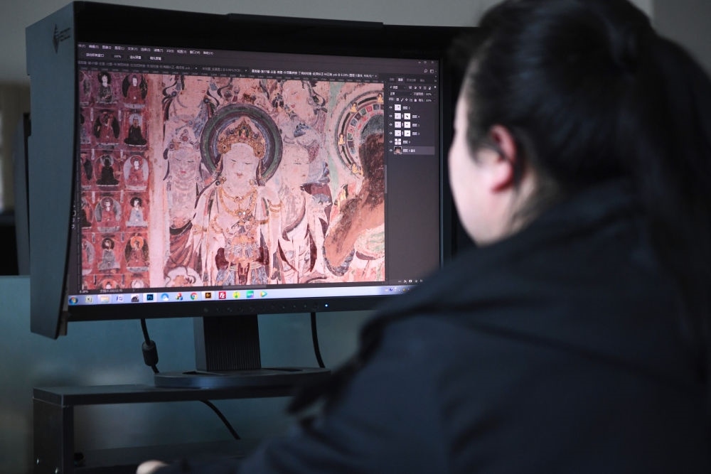 敦煌研究院文物數字化保護團隊圖像處理人員年海麗在拼接壁畫圖像（2023年4月25日攝）。數字化探索為莫高窟的保護與傳承開辟了全新路徑，數字技術讓敦煌文物走出洞窟，跨出國門，走向“永久保存、永續(xù)利用”。新華社記者 陳斌 攝