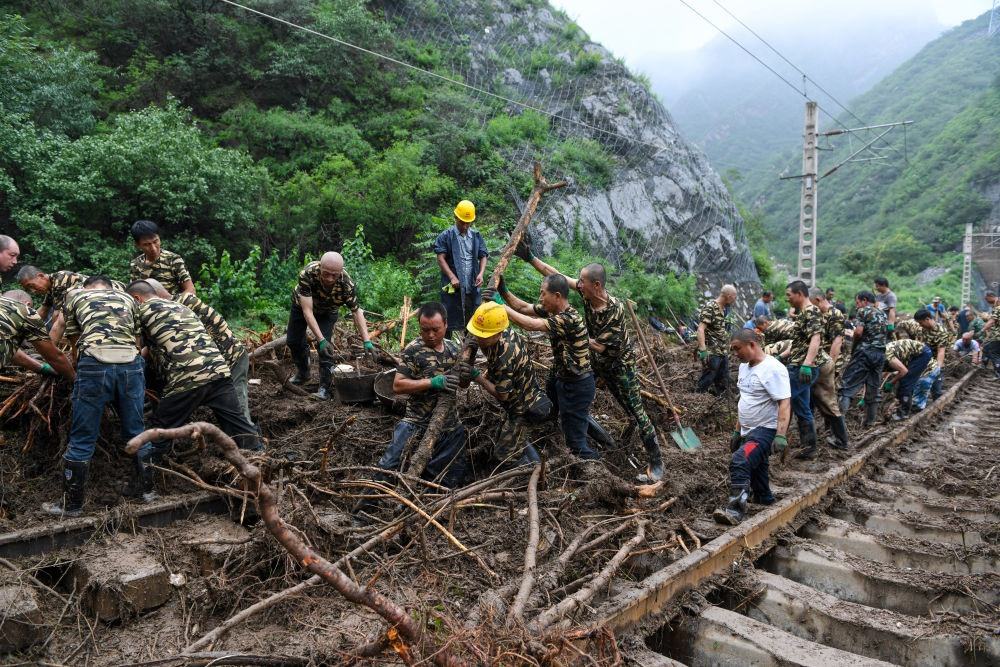 8月1日，在北京市門頭溝區(qū)水峪嘴村附近一段被阻斷的鐵路線上，中鐵六局工作人員在清理軌道上的雜物，全力恢復(fù)交通。新華社記者 鞠煥宗 攝