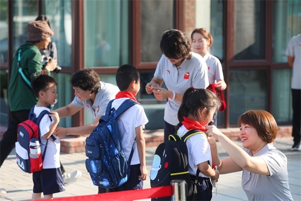 8月30日，雄安史家胡同小學(xué)學(xué)生體驗(yàn)學(xué)校生活。老師為學(xué)生佩戴?；?。
