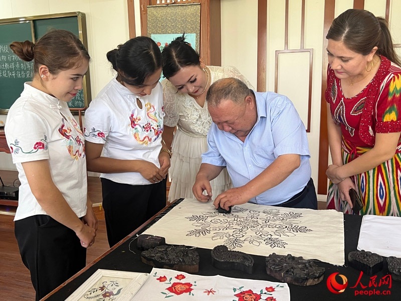 國家級非物質文化遺產(chǎn)模戳印花布技藝傳承人吾吉阿西木?吾舒爾展示模戳印花布的制作過程。人民網(wǎng)記者 常雪梅攝