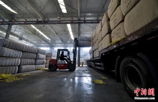 新疆喀什綜合保稅區(qū)，喀什啟路國(guó)際貿(mào)易有限公司的倉(cāng)庫(kù)內(nèi)，工人正在裝載從塔吉克斯坦和烏茲別克斯坦進(jìn)口的棉花。劉新攝