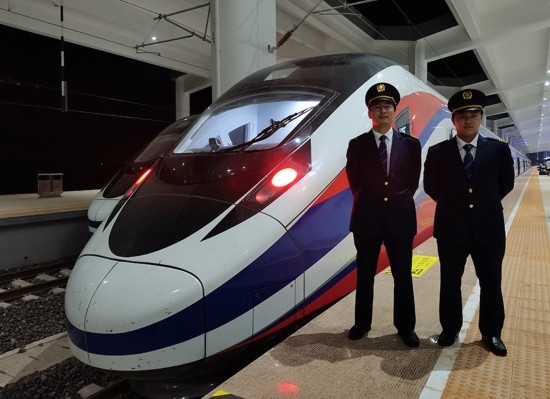 劉銀能（右一）與中國師父鄔俊鴻在動車組前合影。受訪者供圖