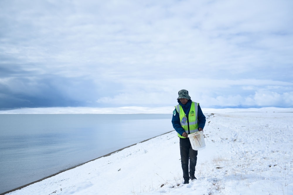 2021年10月20日，在青海省果洛藏族自治州瑪多縣扎陵湖鄉(xiāng)勒那村，三江源國家公園黃河源園區(qū)生態(tài)管護員在扎陵湖邊撿拾垃圾。新華社記者 張龍 攝
