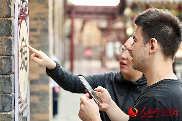 選手安德烈（俄羅斯）在老師指導(dǎo)下學(xué)習(xí)墻壁上張貼的生僻字。人民網(wǎng) 盧鵬宇攝