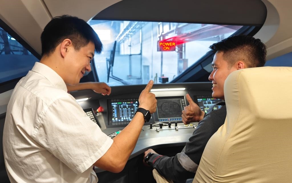 8月25日，在印度尼西亞萬隆的雅萬高鐵德卡魯爾動(dòng)車所內(nèi)，中國(guó)師傅穆振（左）在向印尼火車司機(jī)塞蒂亞萬講解動(dòng)車組出庫(kù)前的上電作業(yè)。