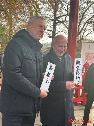 柏林市長韋格納（右）、動物園監(jiān)事會主席布魯克曼（左）手持中國文化中心工作人員現(xiàn)場手書的中文名字。人民網(wǎng)記者 徐馨攝