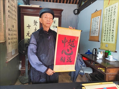 越南首都河內(nèi)文廟內(nèi)，阮明珠展示“中越心相近”書法作品。