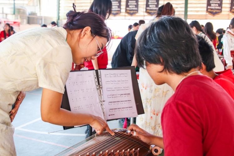 志愿者教師指導學生彈奏古箏?；顒又鬓k方供圖