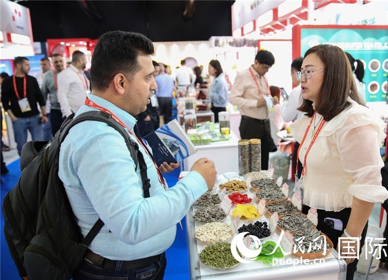 圖為一家中國干果參展企業(yè)代表與采購商洽談。人民網(wǎng) 塔里克·易卜拉欣攝