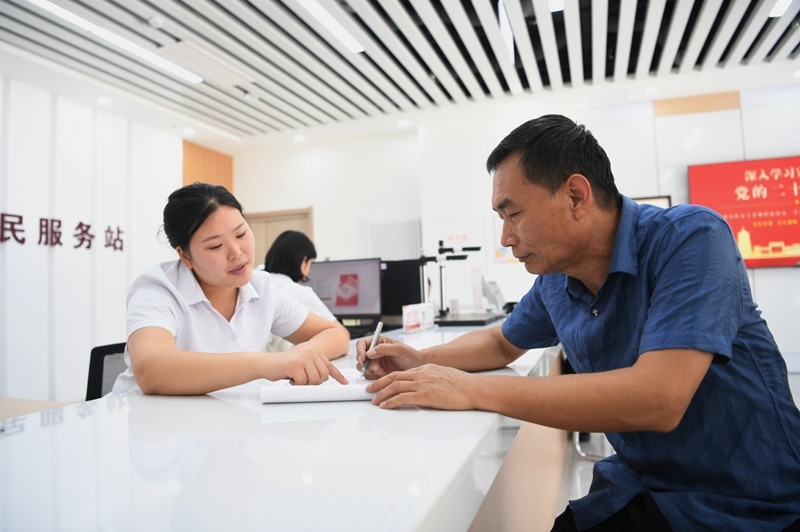 2023年5月23日，河北雄安新區(qū)容東片區(qū)南文營(yíng)社區(qū)居民（右）在社區(qū)便民服務(wù)站辦理業(yè)務(wù)。