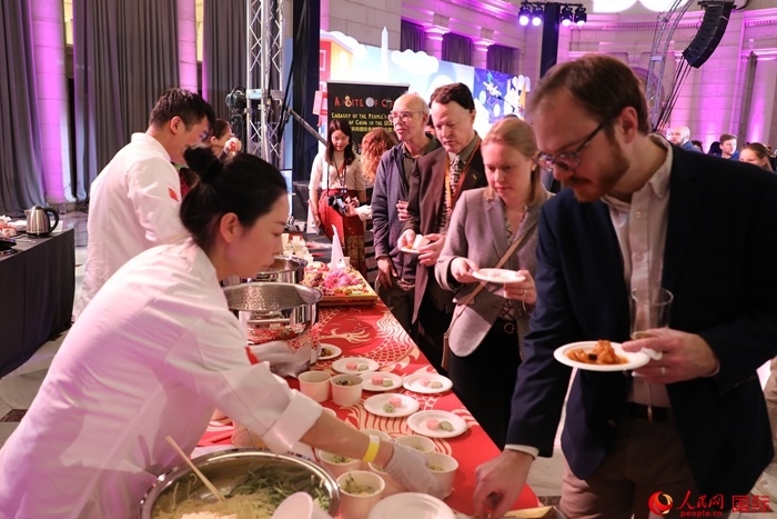 當(dāng)?shù)貢r(shí)間3月7日晚，華盛頓聯(lián)合車站廣場(chǎng)舉行駐美使團(tuán)“使館主廚挑戰(zhàn)賽”。圖為當(dāng)?shù)孛癖娫谥袊?guó)展臺(tái)前體驗(yàn)中國(guó)美食。人民網(wǎng)記者 李志偉攝