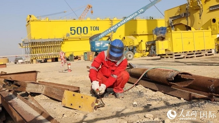 工人正在龍門吊吊裝現(xiàn)場切割金屬件。人民網(wǎng)記者管克江攝