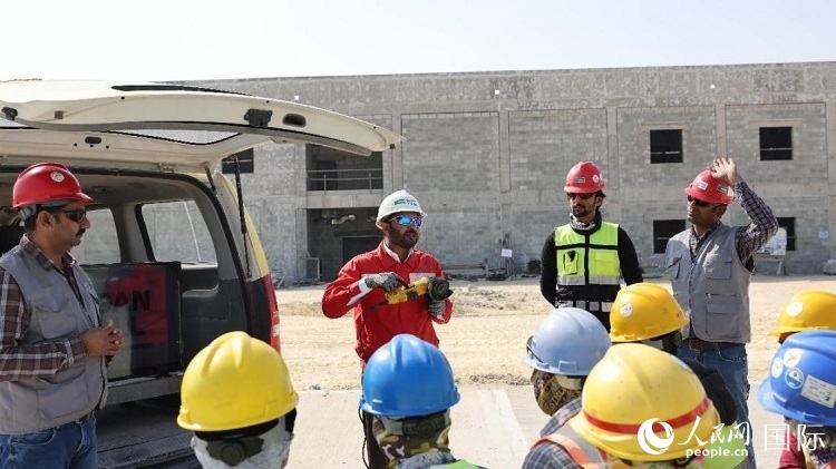 穆薩瓦爾(圖中紅衣人）現(xiàn)場演示工具操作規(guī)范。人民網(wǎng)記者 管克江攝