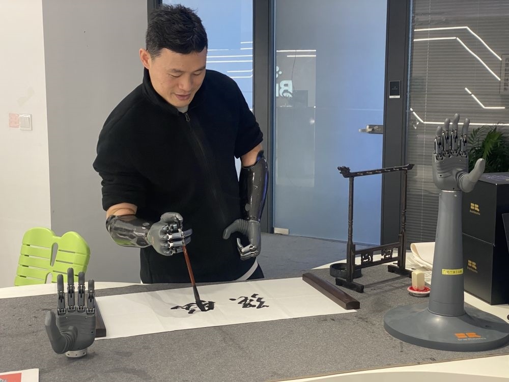 2024年3月29日，在浙江強(qiáng)腦科技有限公司展廳內(nèi)，失去雙手的產(chǎn)品體驗(yàn)官倪敏成依靠智能仿生手寫毛筆字。新華社記者 魏一駿 攝