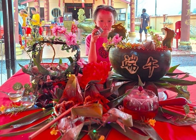 小朋友展示學(xué)裹粽子的成品照。組委會供圖