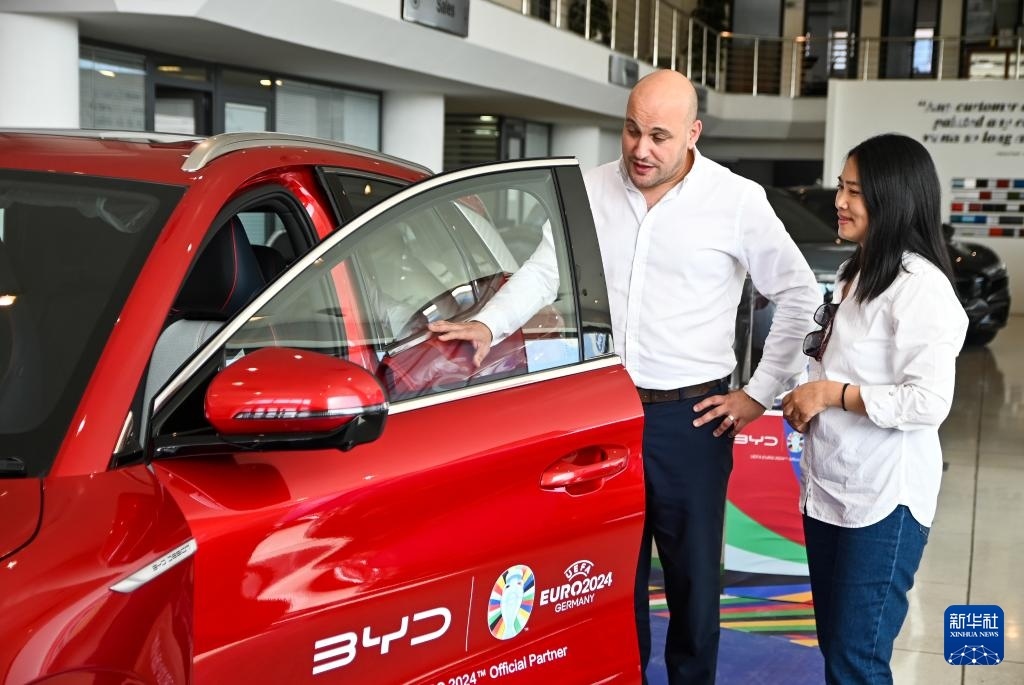2024年5月29日，在馬耳他比爾基卡拉，馬耳他哈桑-扎米特汽車公司首席執(zhí)行官德古阿拉（左）介紹一輛比亞迪純電動(dòng)汽車。新華社發(fā)（喬納森·博格 攝）