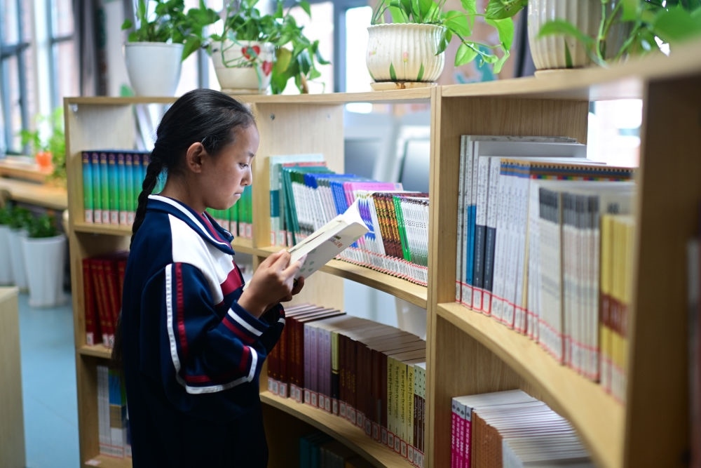 6月18日，果洛西寧民族中學學生尼東拉毛在圖書室看書。