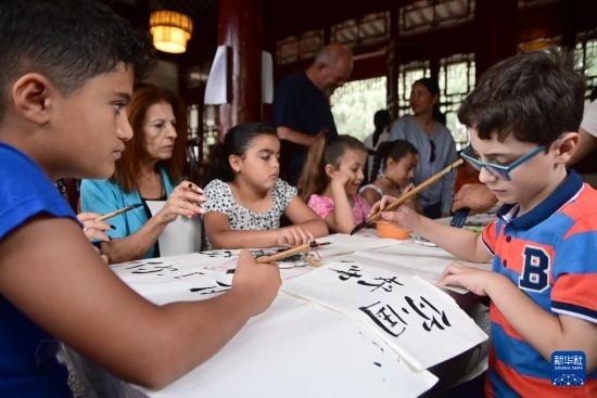 7月4日，在馬耳他桑塔露琪亞市的中國古典園林“靜園”，人們體驗(yàn)中國書法。新華社發(fā)（喬納森·博格 攝）