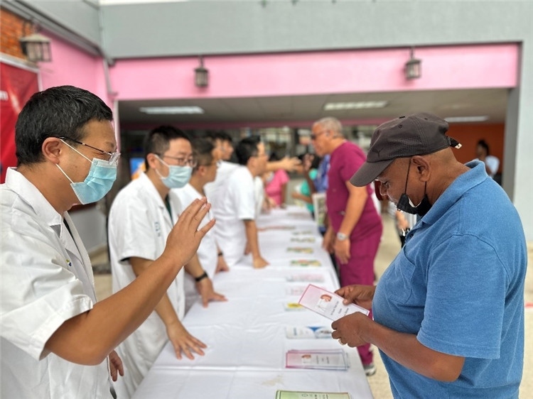 援圭醫(yī)療隊隊員們在啟動儀式上為當(dāng)?shù)孛癖姺职l(fā)宣傳手冊。中國援助圭亞那醫(yī)療隊供圖