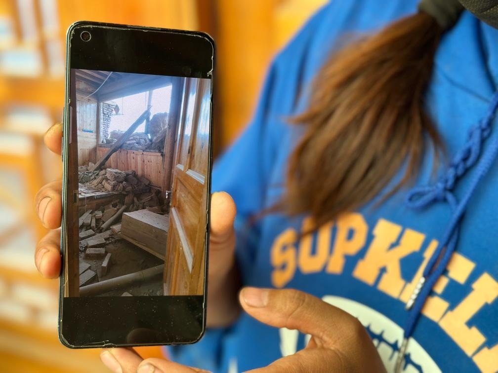 圖為7月17日拉毛東智在手機(jī)上找出地震后房屋受損的照片。新華社記者 張子琪 攝