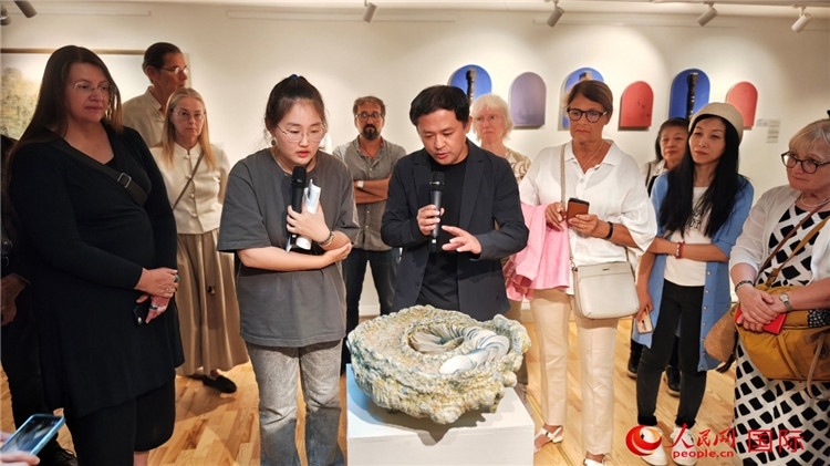 參展人、景德鎮(zhèn)陶瓷大學(xué)設(shè)計藝術(shù)學(xué)院副院長余劍峰（中）向來賓介紹參展作品。人民網(wǎng)記者 殷淼攝