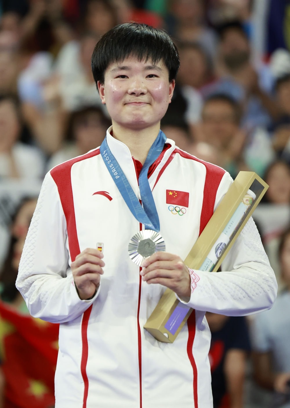 巴黎奧運會羽毛球女子單打亞軍、中國選手何冰嬌在頒獎儀式上一手握著銀牌，一手握著西班牙奧委會徽章（2024年8月5日攝）。新華社記者 任正來 攝