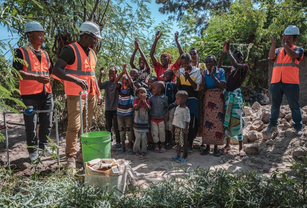 2023年6月13日，在坦桑尼亞姆萬扎省米松圭，工作人員接通水管后贏得當(dāng)?shù)鼐用窆恼茪g呼。新華社記者 王冠森 攝