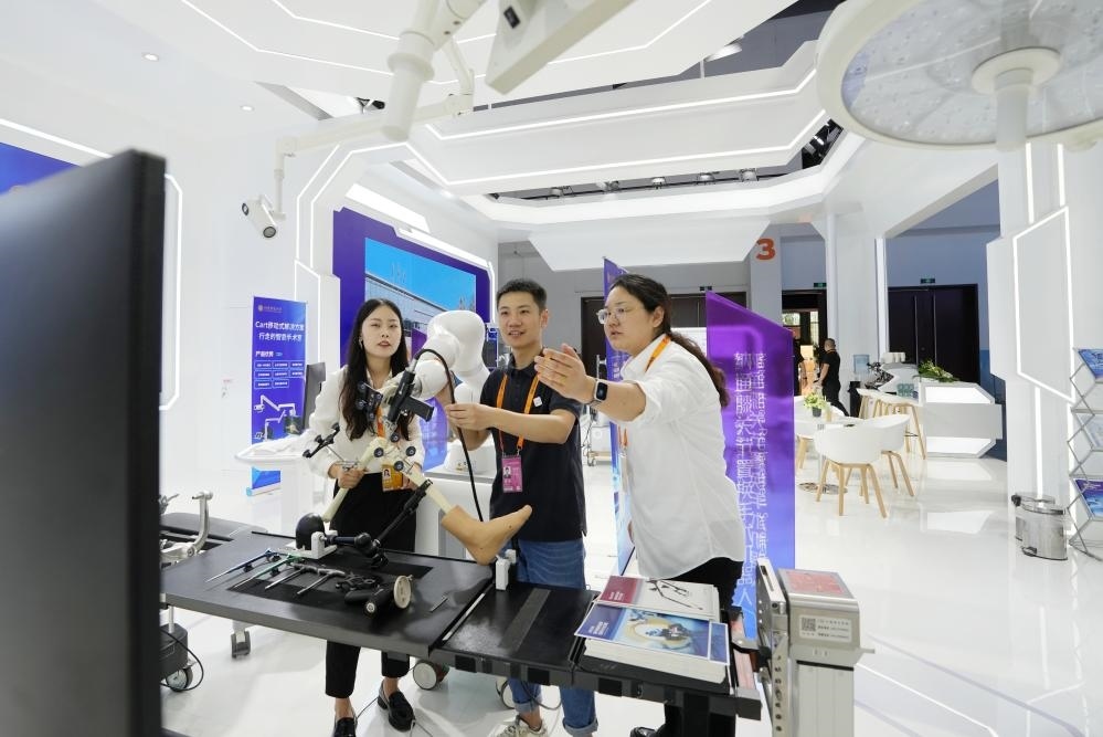 9月11日，一位媒體記者（中）在2024年服貿(mào)會(huì)國家會(huì)議中心會(huì)場(chǎng)體驗(yàn)北京納通科技集團(tuán)有限公司的膝關(guān)節(jié)置換手術(shù)機(jī)器人。新華社記者鞠煥宗 攝