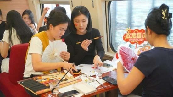 10月1日，旅客們在G1634次列車上給油紙傘作畫。新華社記者周義 攝