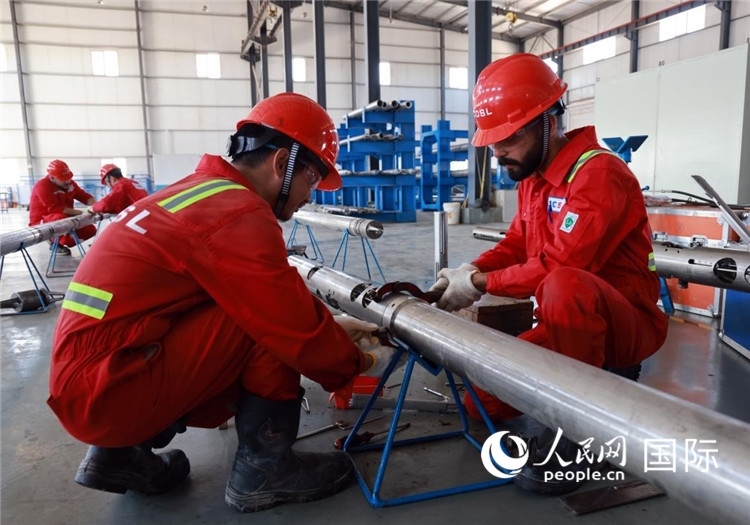 中伊員工共同在檢修鉆井設備。人民網(wǎng)記者管克江攝
