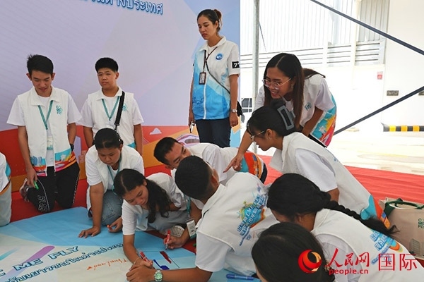 泰國(guó)學(xué)生在開(kāi)營(yíng)儀式展板上繪制圖案。人民網(wǎng)記者 白元琪攝