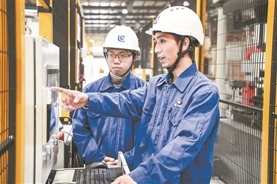 在廣西柳工機(jī)械股份有限公司生產(chǎn)車間內(nèi)，一名高級技師（右）給徒弟講解數(shù)控設(shè)備操作細(xì)節(jié)。新華社記者 曹祎銘攝