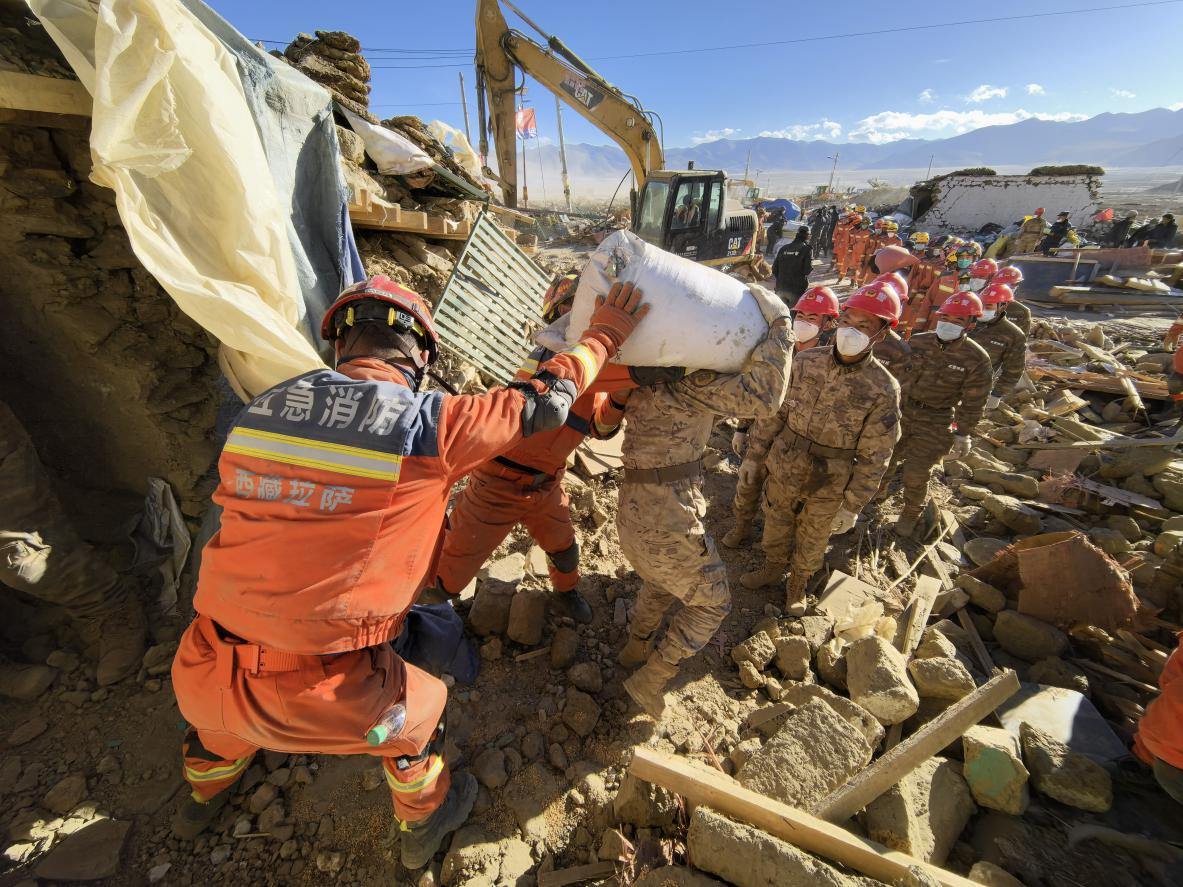1月11日，定日縣長所鄉(xiāng)古榮村，應(yīng)急消防等救援人員排隊接力搶運掩埋在倒塌房屋下的群眾財物。人民日報記者楊翹楚攝