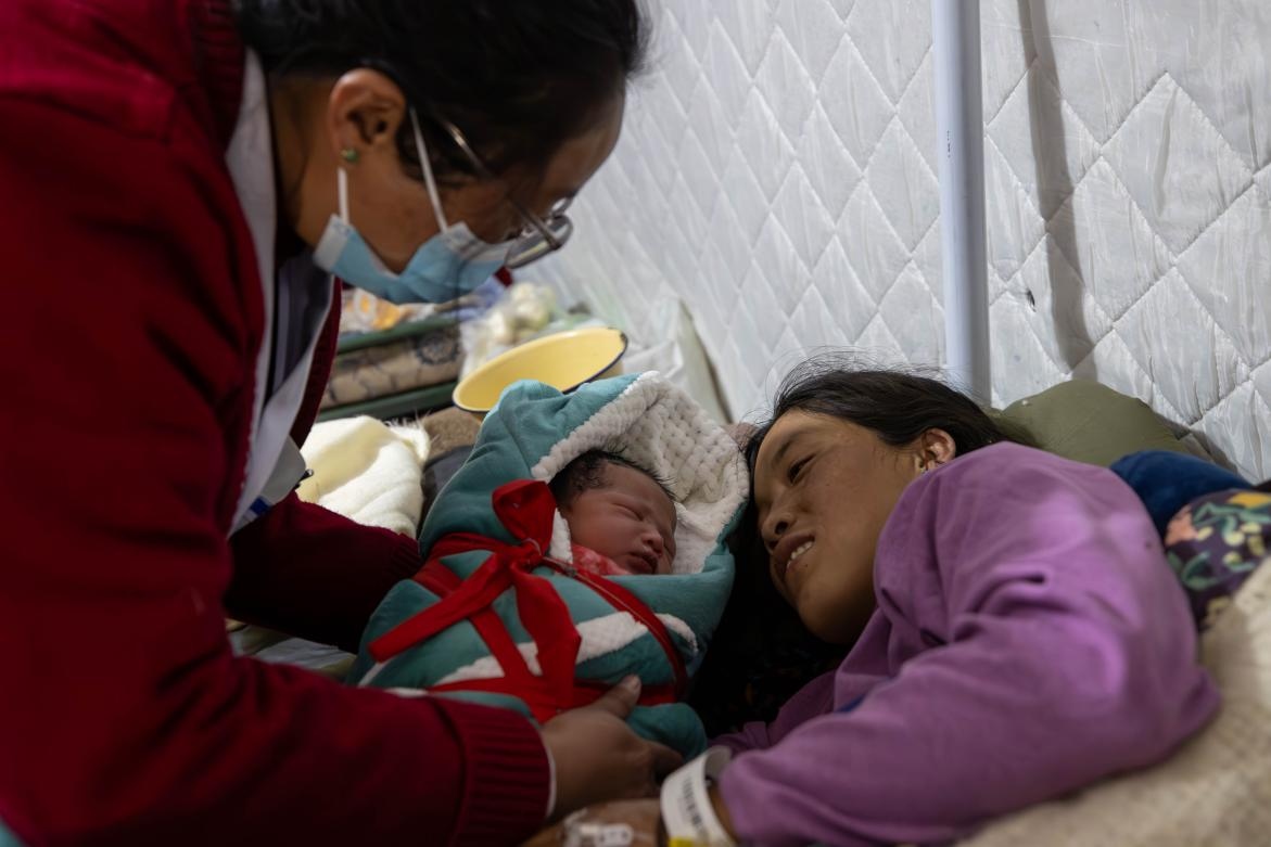 1月10日，定日縣中心醫(yī)院的婦產(chǎn)科醫(yī)生悉心照看一位母親和她懷里的新生兒。人民日報記者張武軍攝