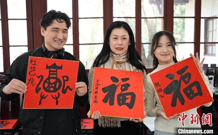 1月20日，外籍留學(xué)生和西泠印社社員李硯(中)展示各自創(chuàng)作的福貼。當(dāng)日，來(lái)自巴西、馬來(lái)西亞、加納、哈薩克斯坦的外籍留學(xué)生在浙江杭州西泠印社體驗(yàn)福貼、春聯(lián)和篆刻，感受古老的中國(guó)傳統(tǒng)文化。中新社記者 王剛 攝