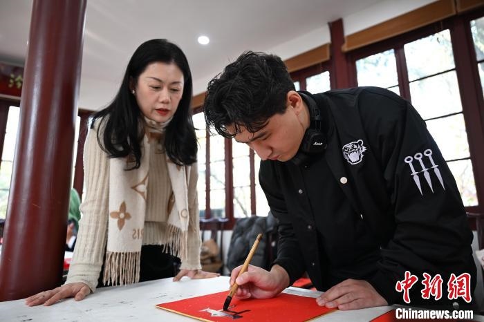 1月20日，外籍留學(xué)生在西泠印社社員李硯指導(dǎo)下寫福。當(dāng)日，來(lái)自巴西、馬來(lái)西亞、加納、哈薩克斯坦的外籍留學(xué)生在浙江杭州西泠印社體驗(yàn)福貼、春聯(lián)和篆刻，感受古老的中國(guó)傳統(tǒng)文化。中新社記者 王剛 攝