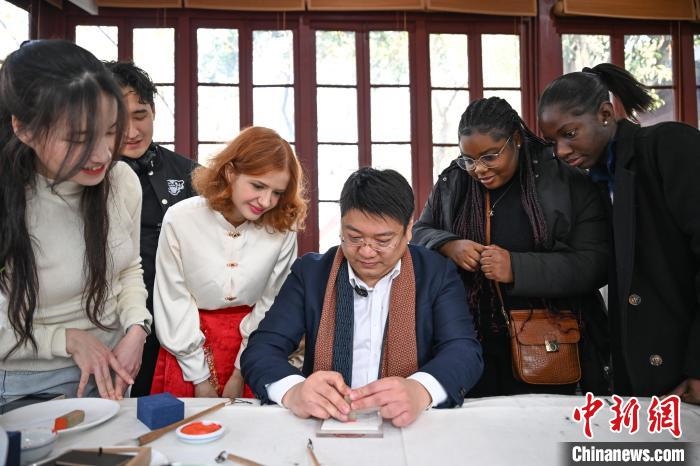 1月20日，篆刻家王臻向外籍留學(xué)生展示篆刻印章。當(dāng)日，來(lái)自巴西、馬來(lái)西亞、加納、哈薩克斯坦的外籍留學(xué)生在浙江杭州西泠印社體驗(yàn)福貼、春聯(lián)和篆刻，感受古老的中國(guó)傳統(tǒng)文化。中新社記者 王剛 攝
