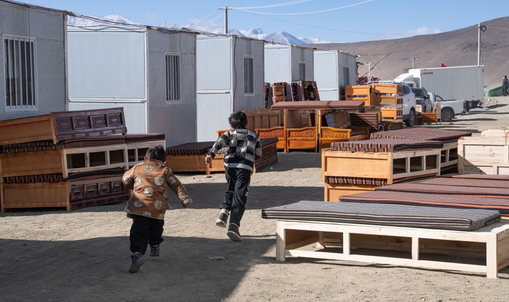 2025年1月13日，在定日縣嘎旦村，兩個(gè)孩子在剛運(yùn)來(lái)的兩排藏床間奔跑。新華社記者丁增尼達(dá) 攝