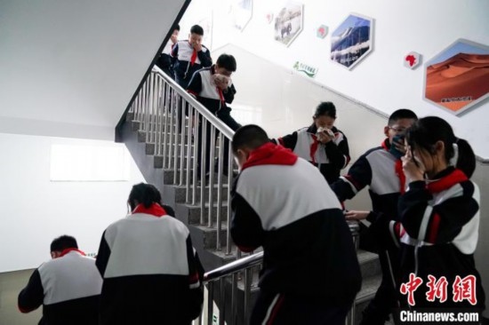  圖為學(xué)生們進(jìn)行應(yīng)急疏散演練。中新社記者 趙宇航 攝